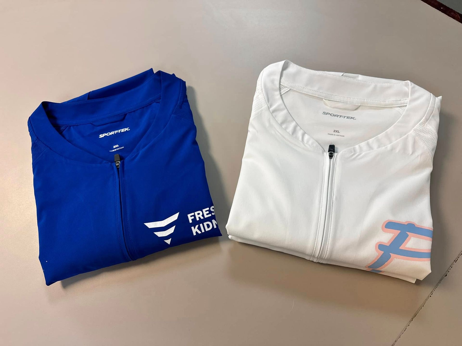 A blue shirt and a white shirt are folded on a table.