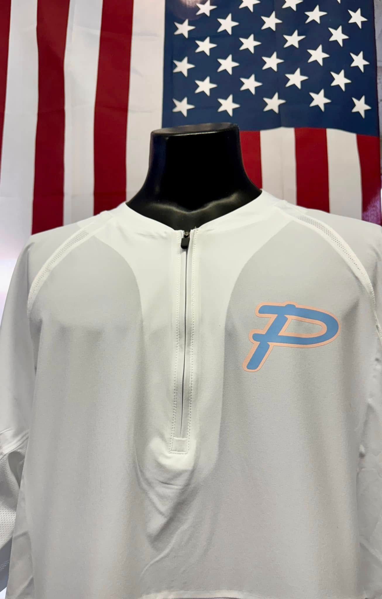 A white shirt with the letter p on it is on a mannequin in front of an american flag