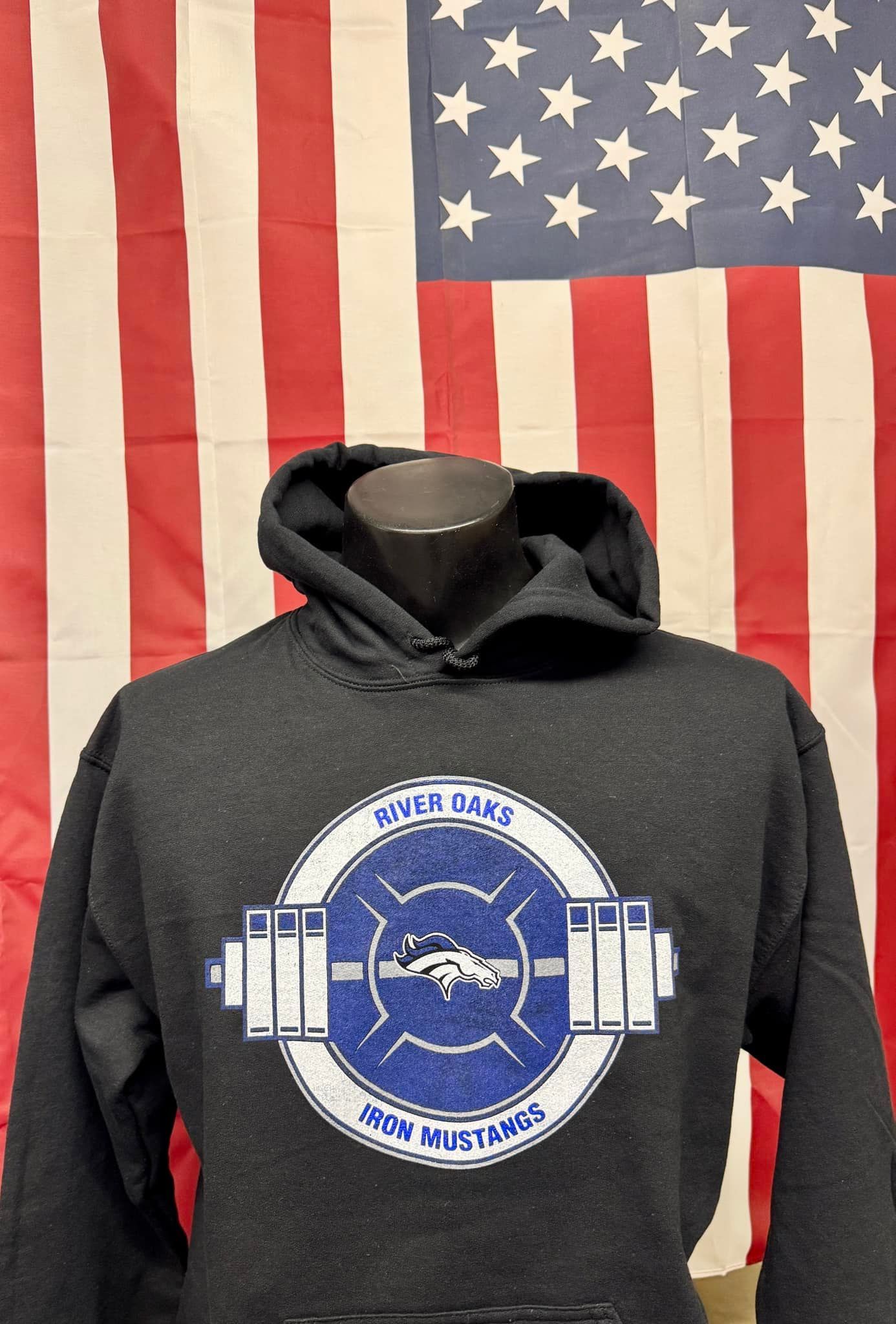 A black hoodie is on a mannequin in front of an american flag