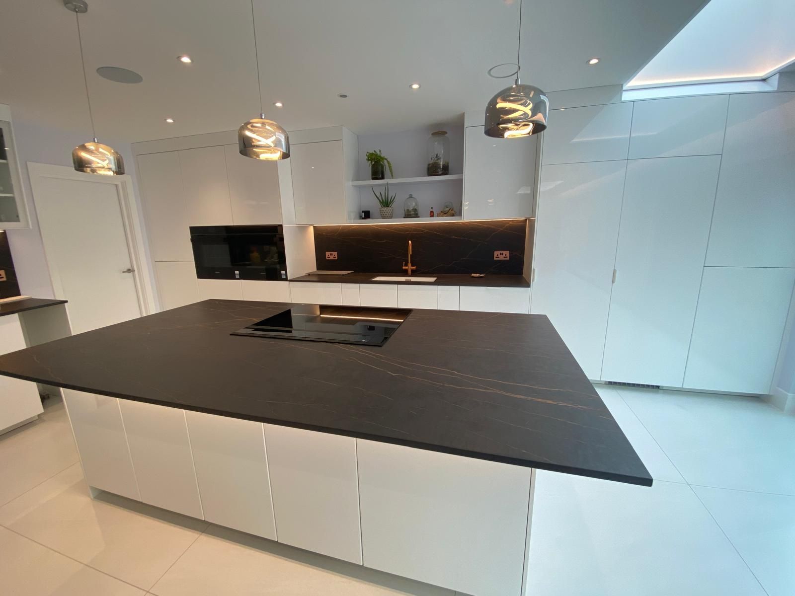 Modern white kitchen with a large dark island and hanging pendant lights