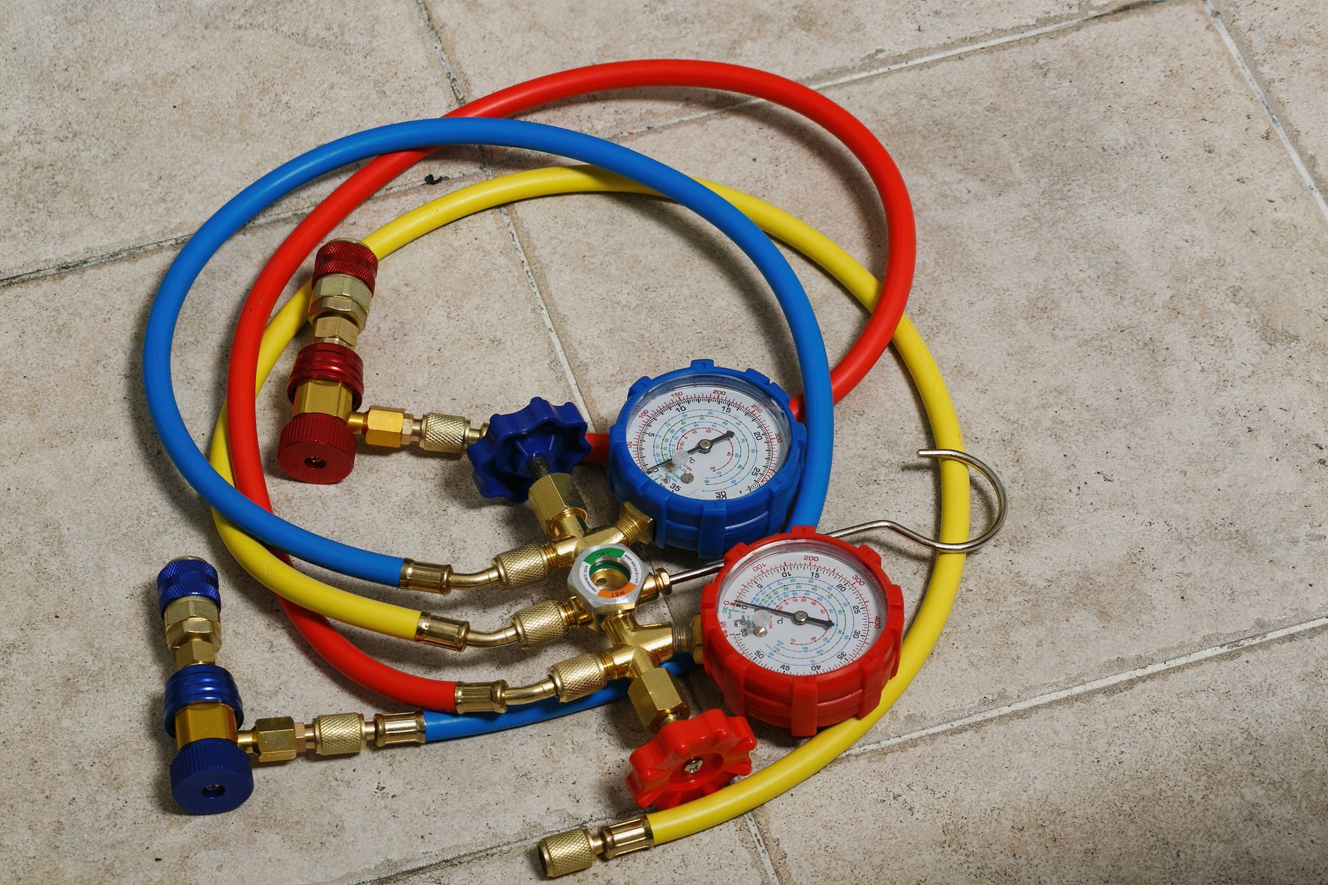Close-up of HVAC manifold gauge set with red, blue, and yellow hoses.