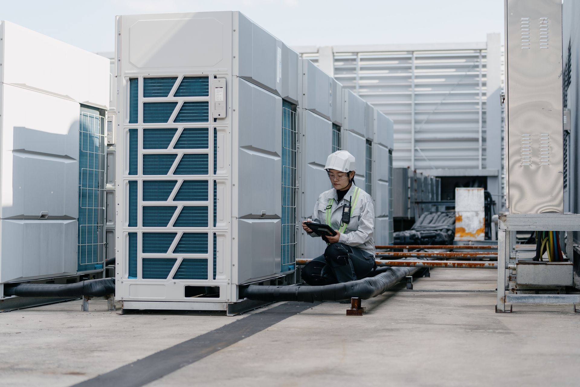 Technician performing HVAC system maintenance on rooftop commercial air conditioning units.