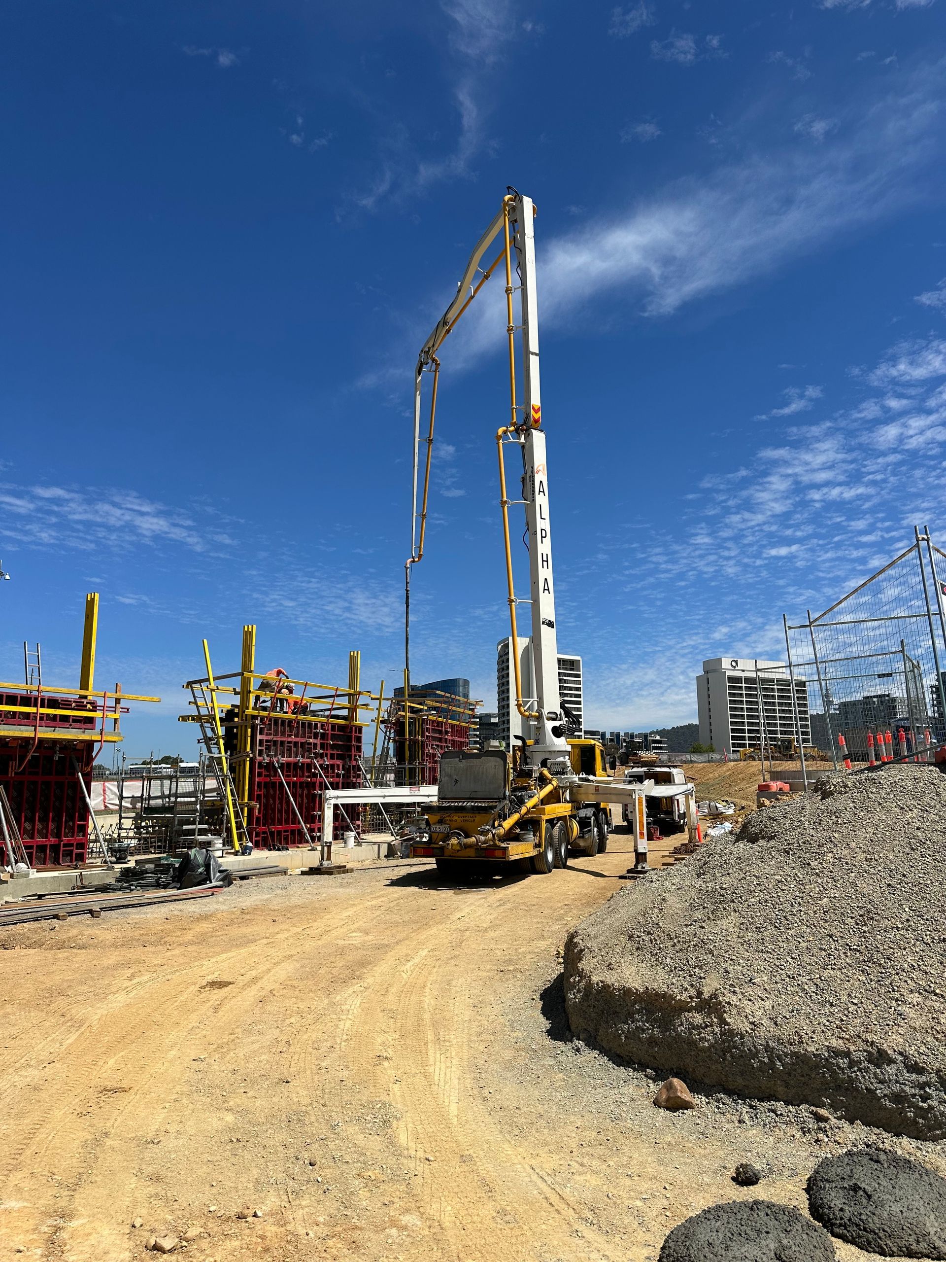 Two construction workers are pouring concrete into a foundation.