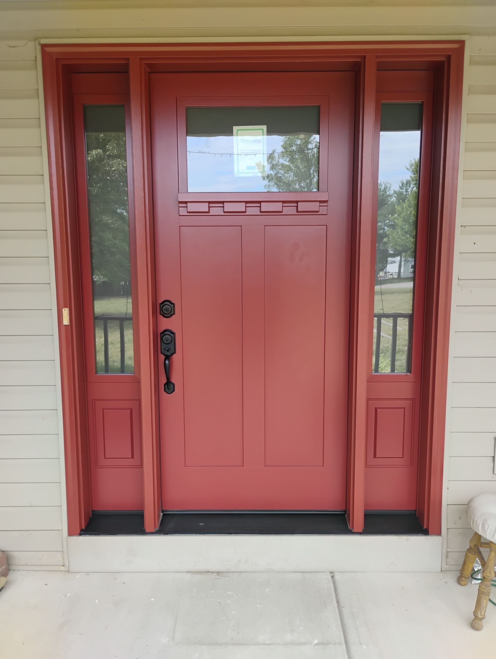 red front door with glass window panel and two glass window panels on the side
