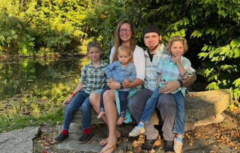 A house with a green roof and pink flowers in front of it
