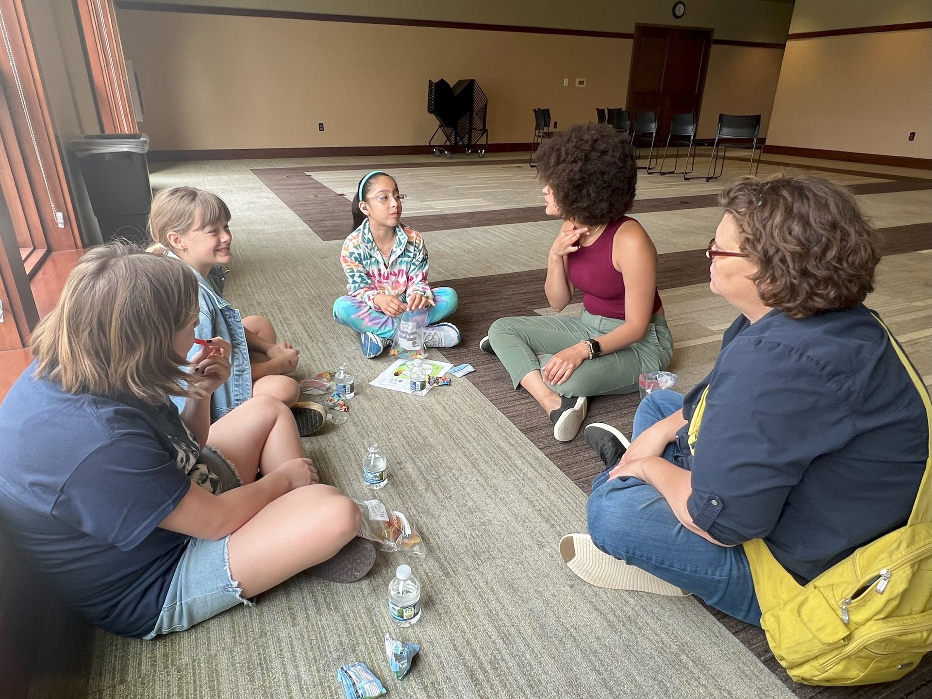 A group of people are sitting in a circle on the floor in a room.