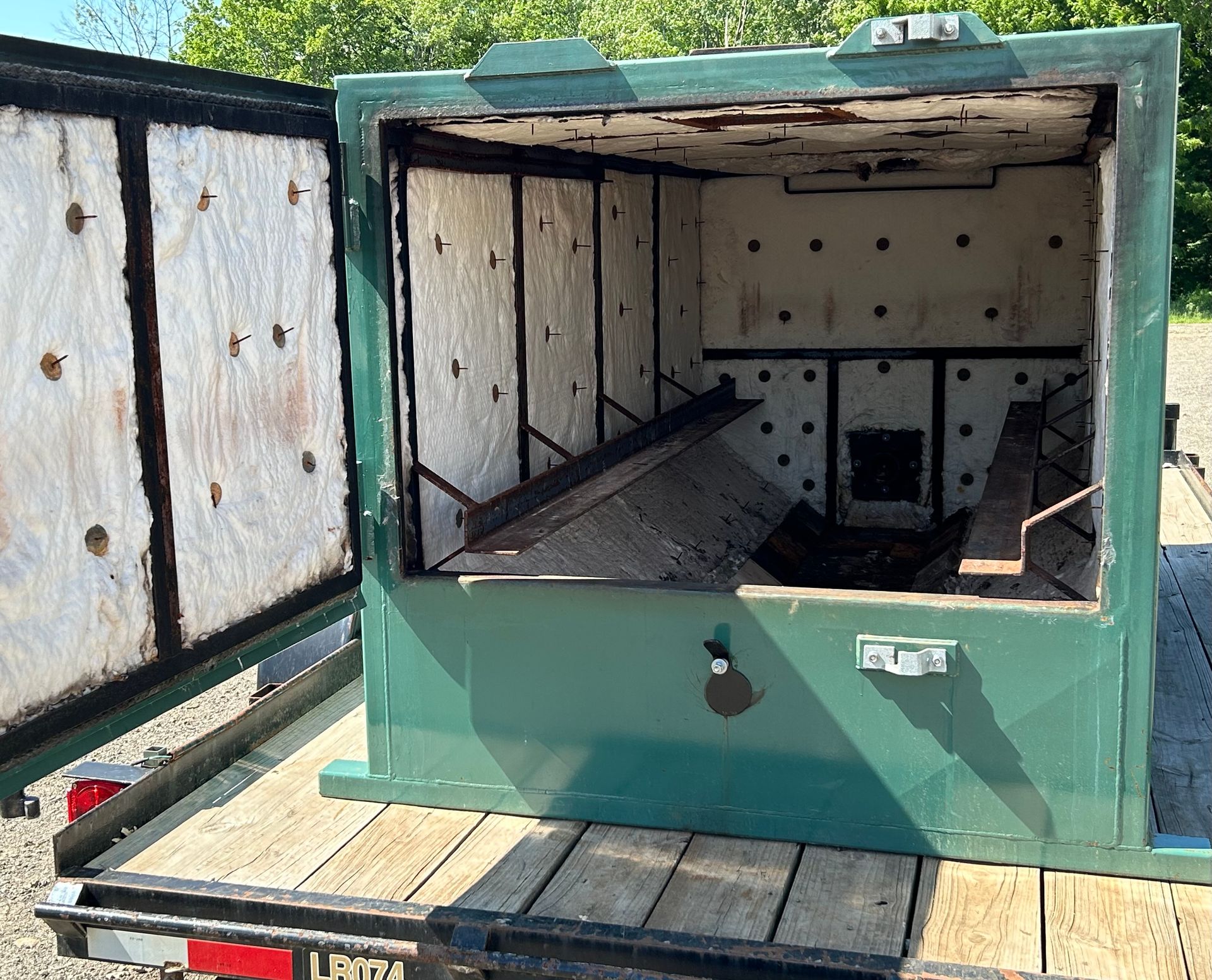 The rear door of the Maine Kiln is open and showing the white insulated walls inside of the kiln painted green.