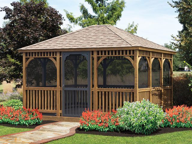 Wooden gazebo with screened walls, brown roof, set in a garden with red flowers and green bushes.