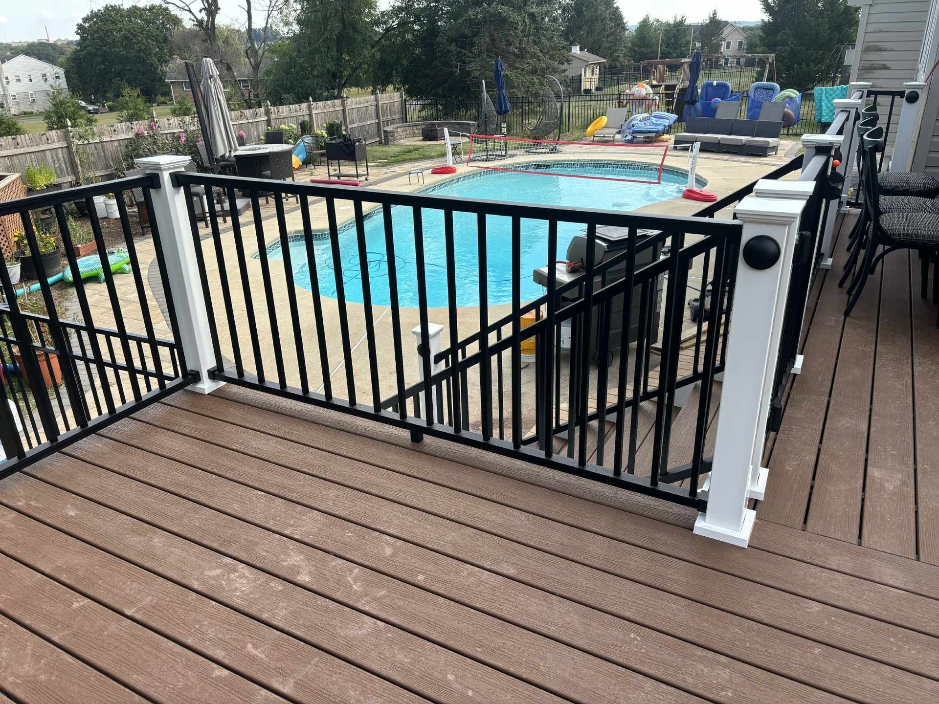Deck with black railing overlooking a blue swimming pool.