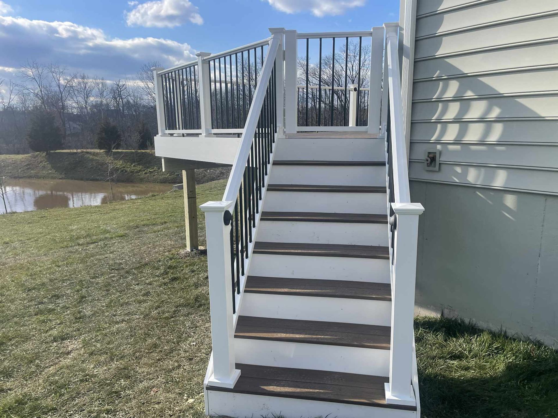 Staircase leading up to a deck with white railings and dark brown steps.