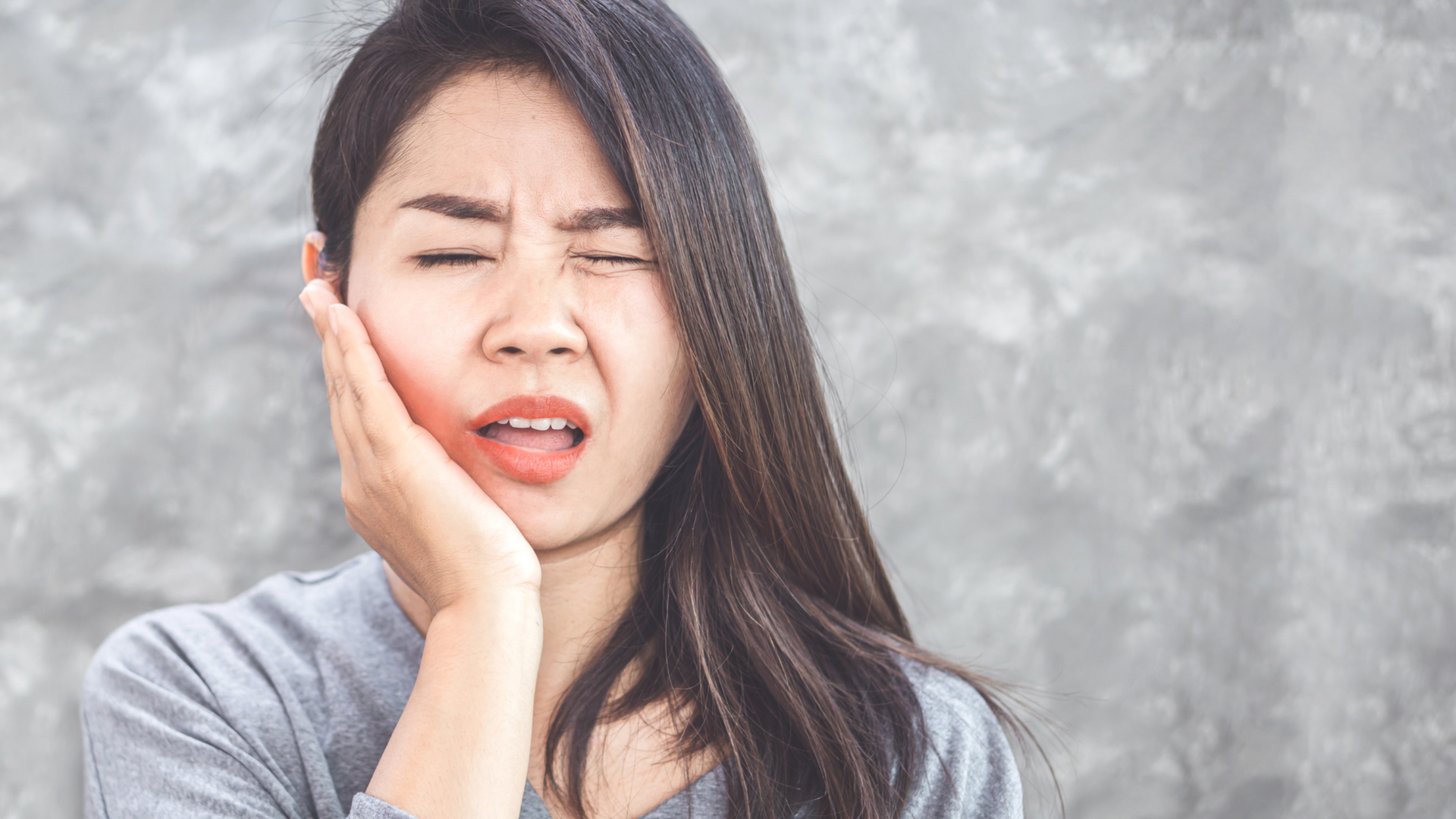 a woman is holding her face in pain because of a toothache .