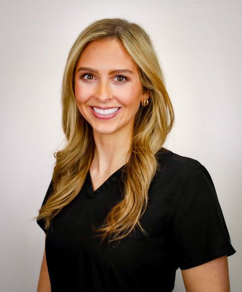 A woman in a black scrub top is smiling for the camera.