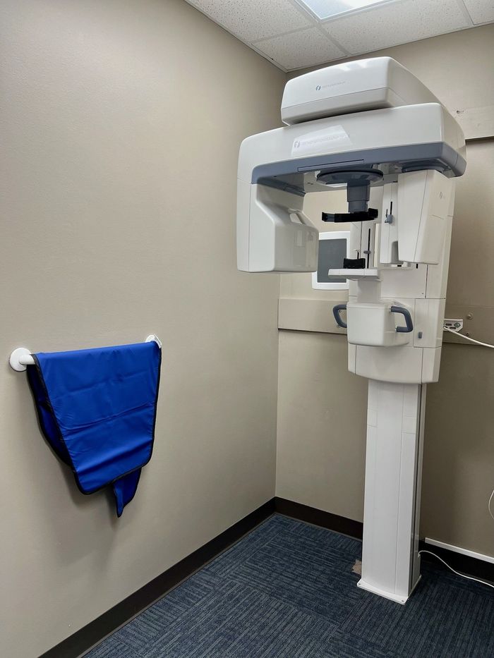 a room with a dental x-ray machine and a blue towel hanging on the wall .