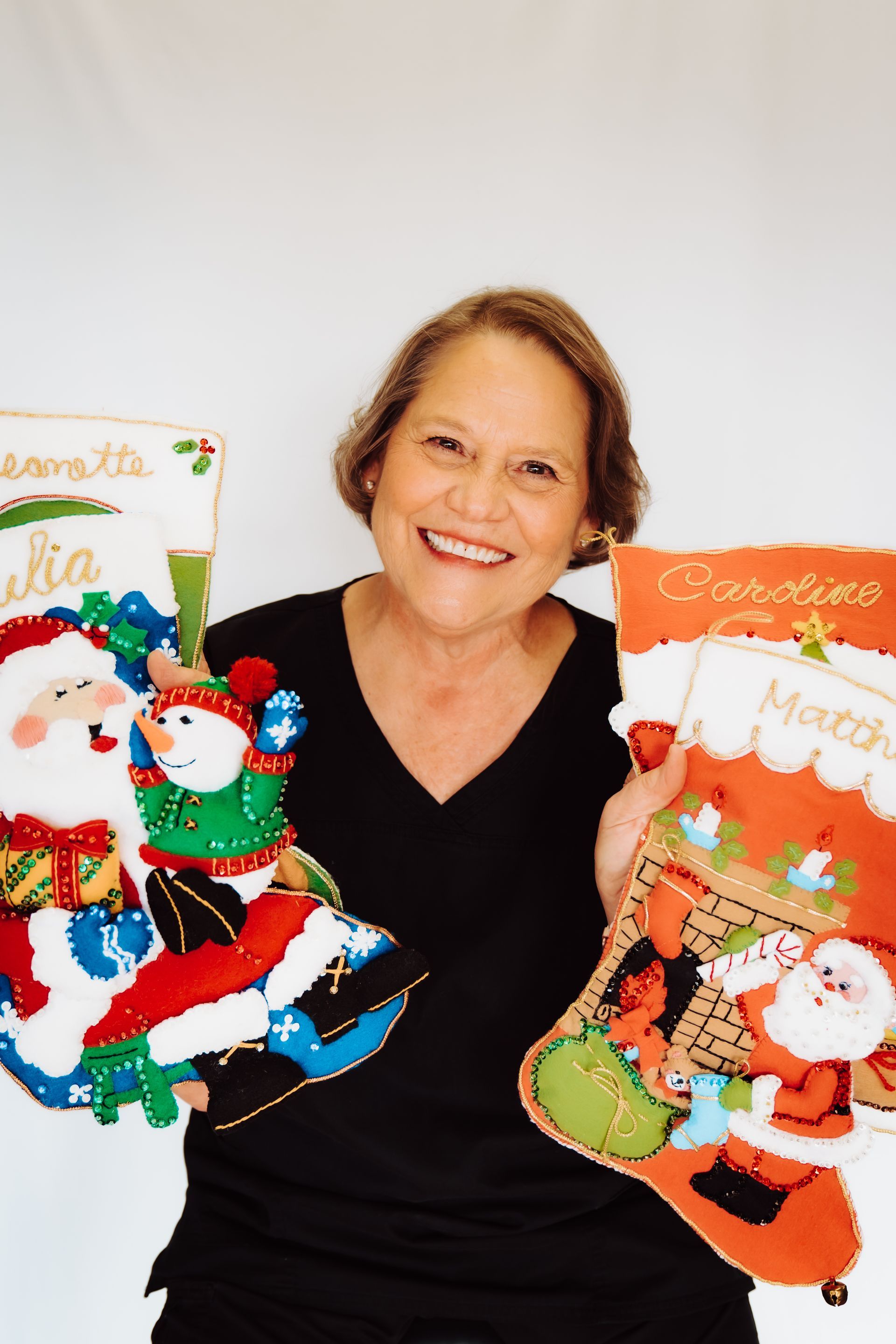 a woman in a black shirt is holding two christmas stockings