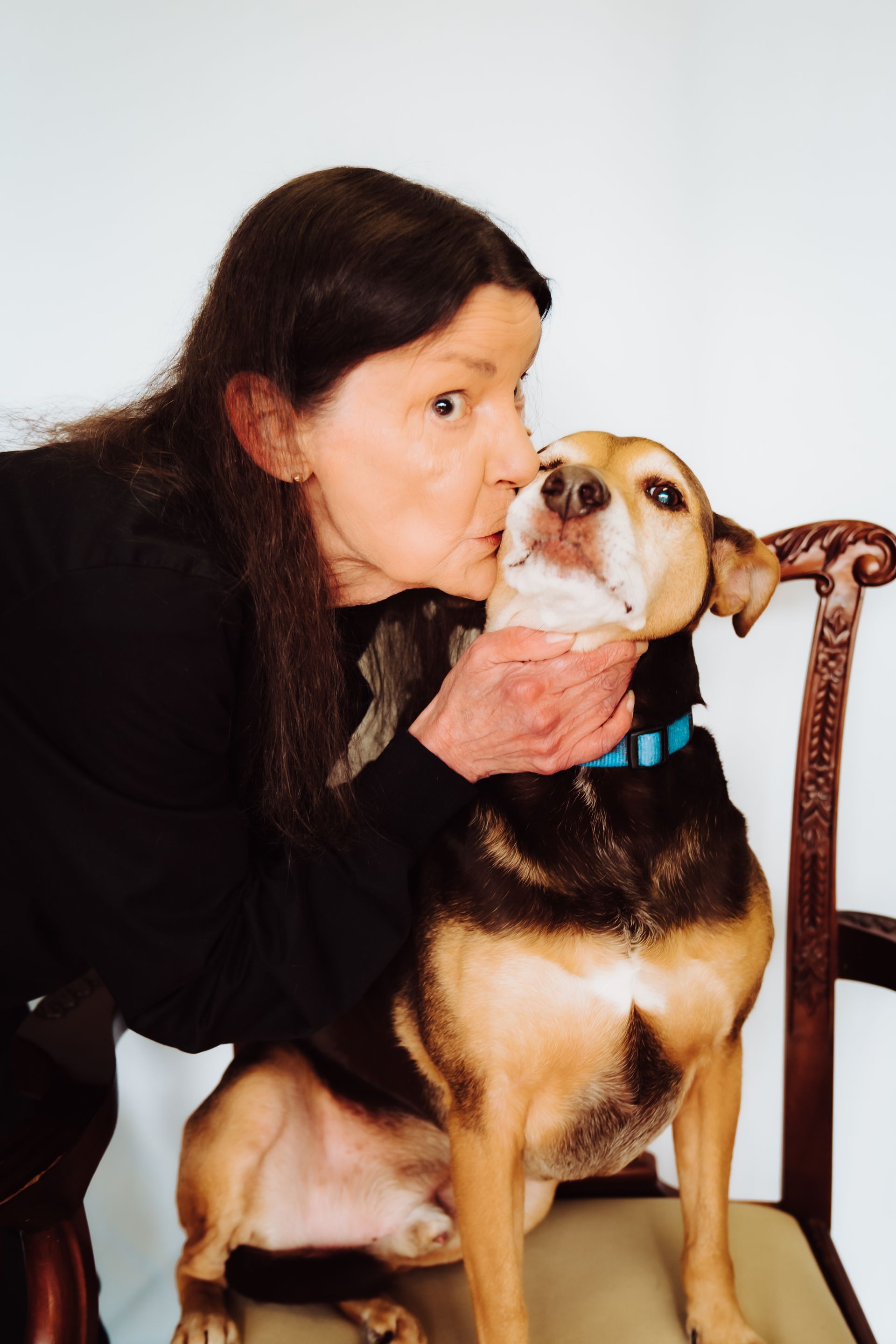 a woman is kissing a brown dog on the nose