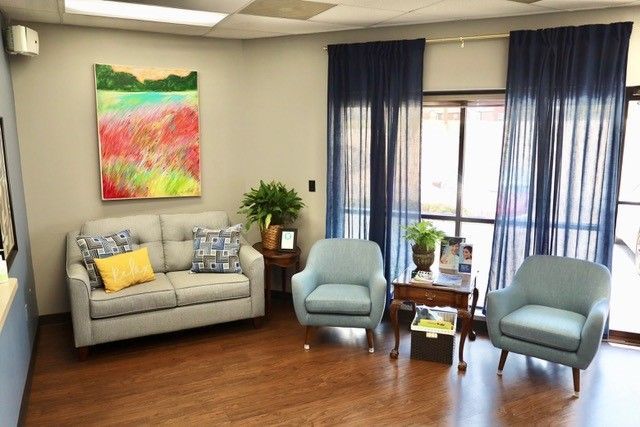 a living room with a couch and two chairs and a painting on the wall .