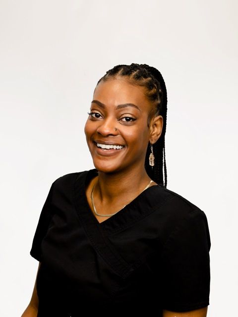 A woman in a black scrub top is smiling for the camera.