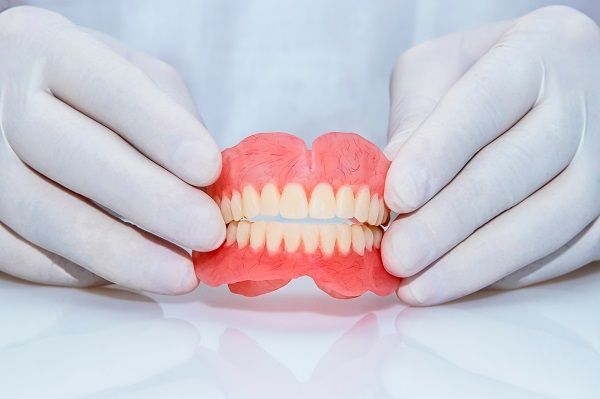 a person is holding a denture in their hands .