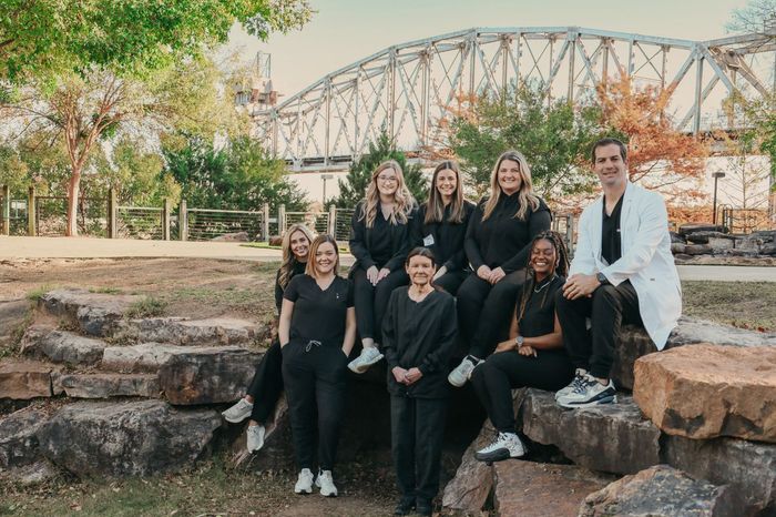 A group of people are sitting on rocks in front of a bridge.