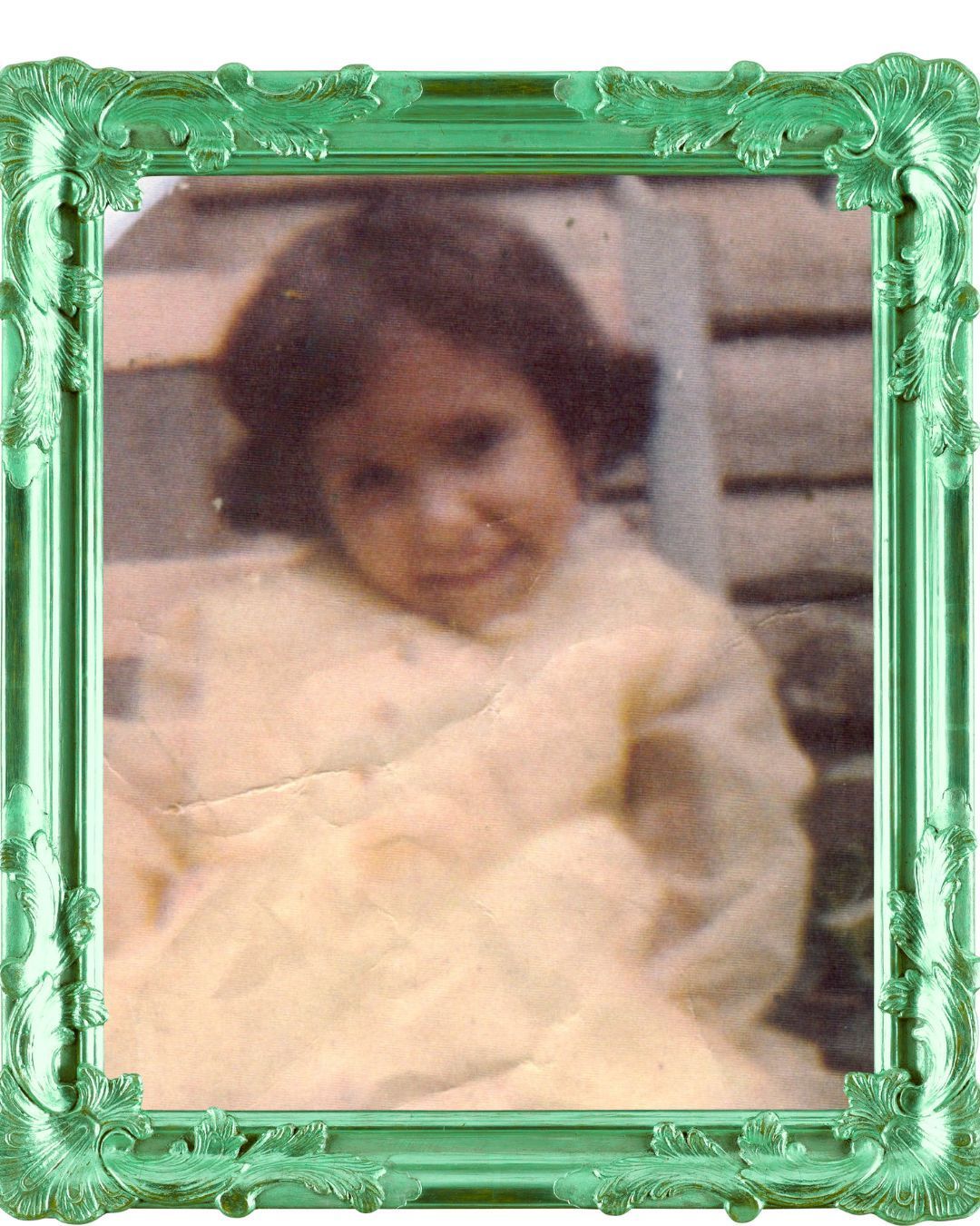 Child in yellow dress smiles in a green ornate frame.