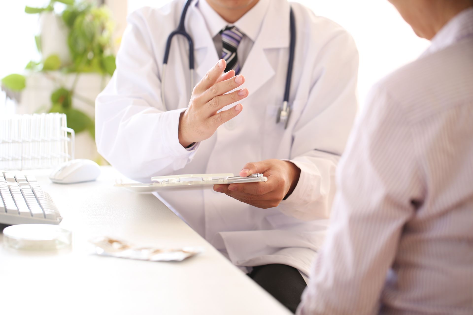A doctor is talking to a patient who is sitting at a desk.