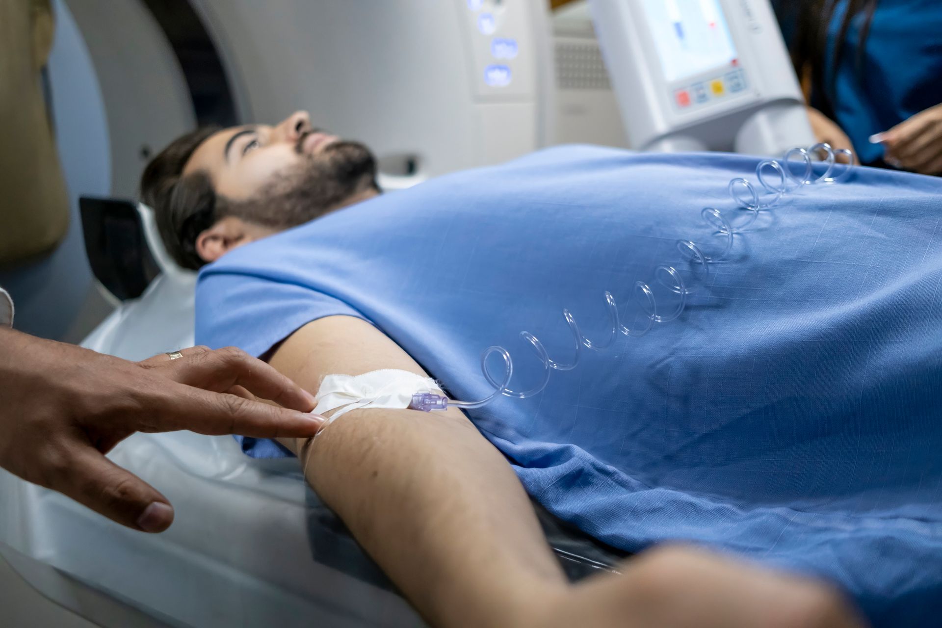 A man is laying in a hospital bed with a needle in his arm.