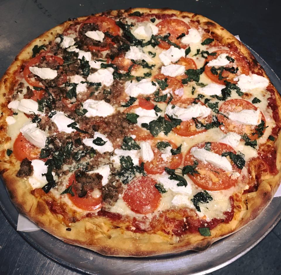 A pizza with tomatoes and cheese on a pan