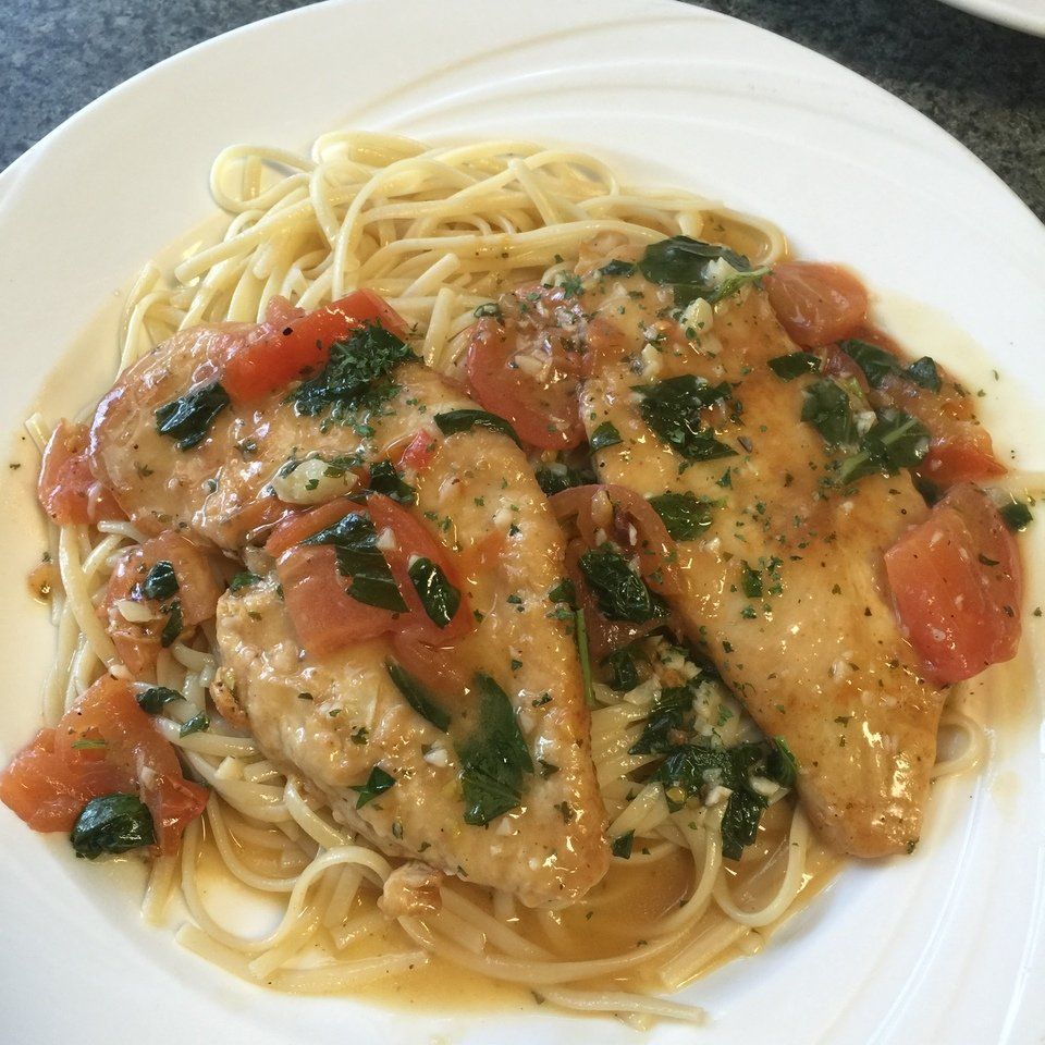 A white plate topped with noodles chicken and tomatoes