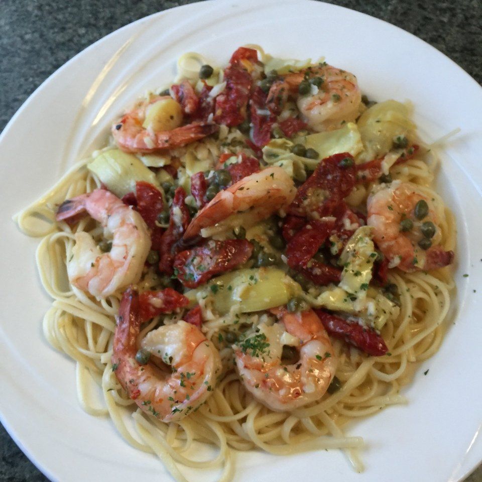 A white plate topped with spaghetti shrimp and vegetables