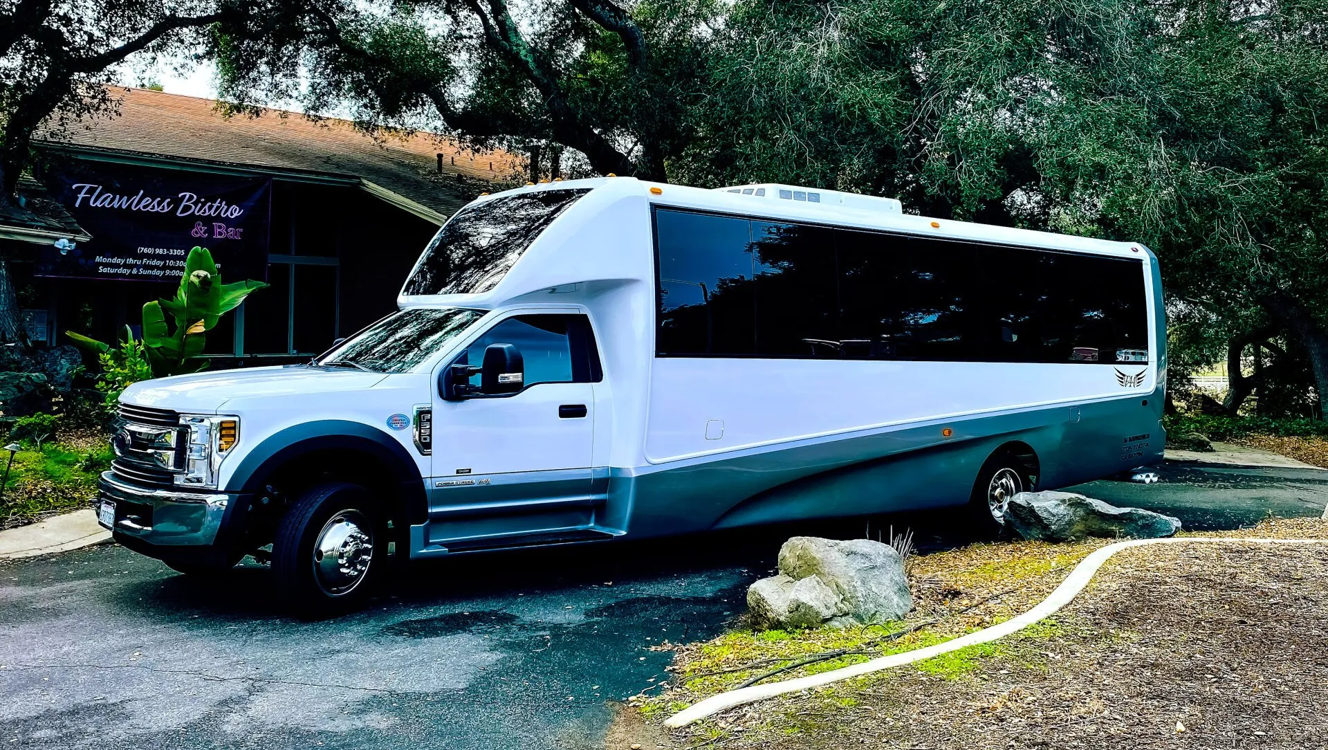 a white bus is parked in a parking lot in front of a building .