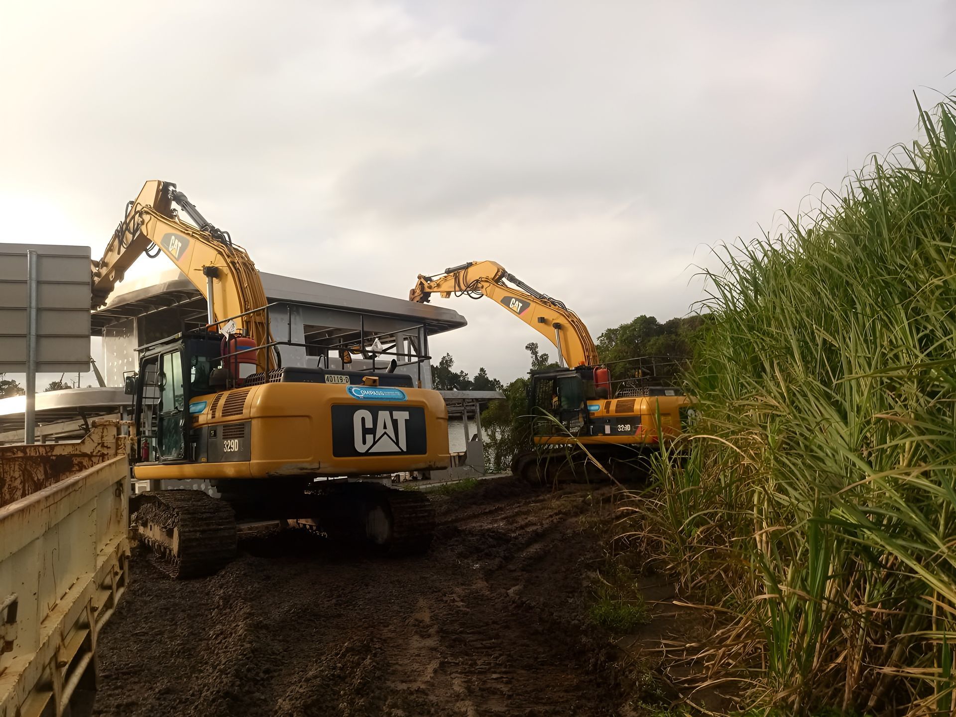Two Yellow CAT Excavators on a Muddy Construction Site — Compass Equipment Hire in Woodburn, NSW