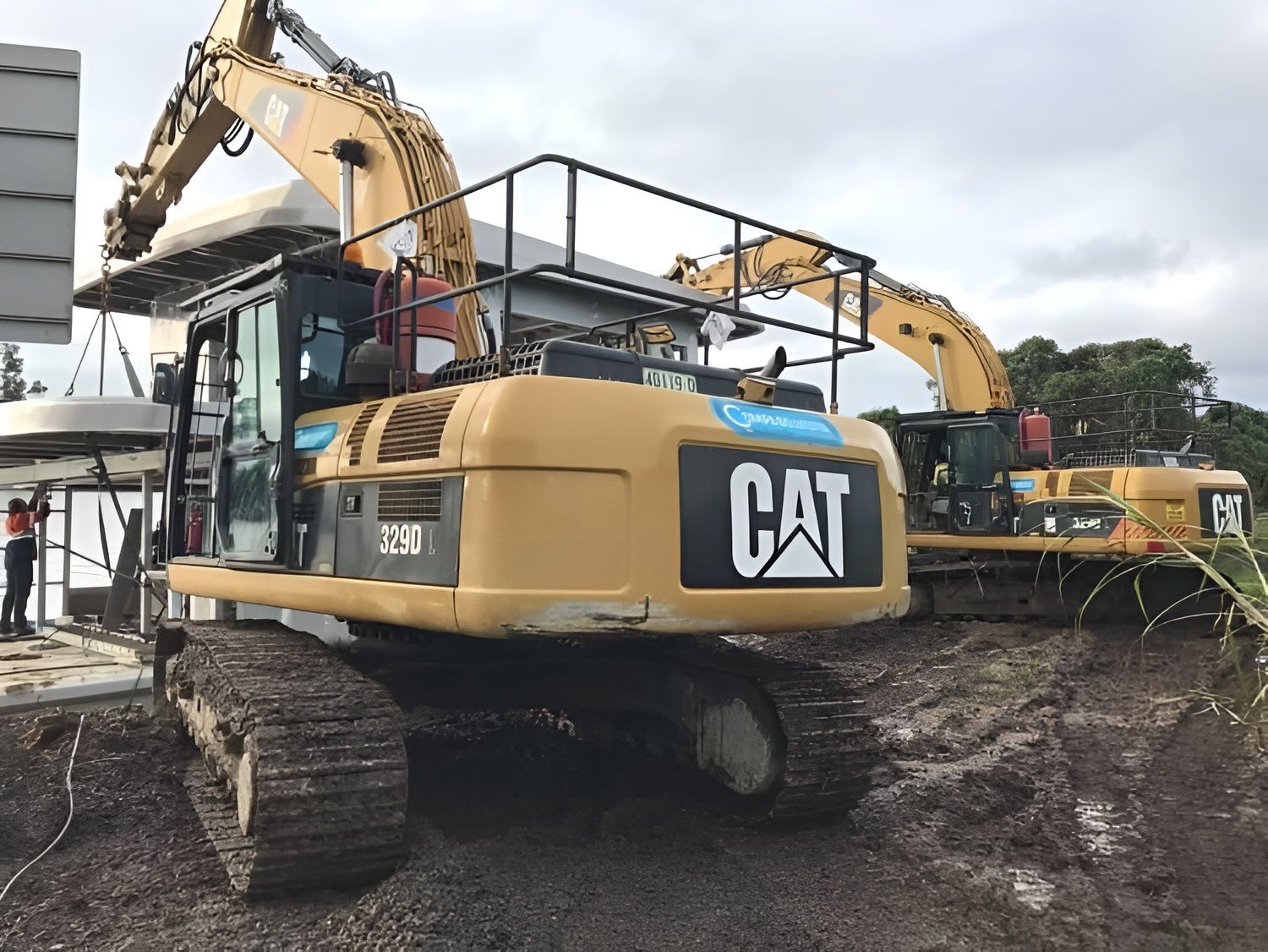 Two Yellow CAT Excavators Lift a Large Concrete Structure — Compass Equipment Hire in Woodburn, NSW