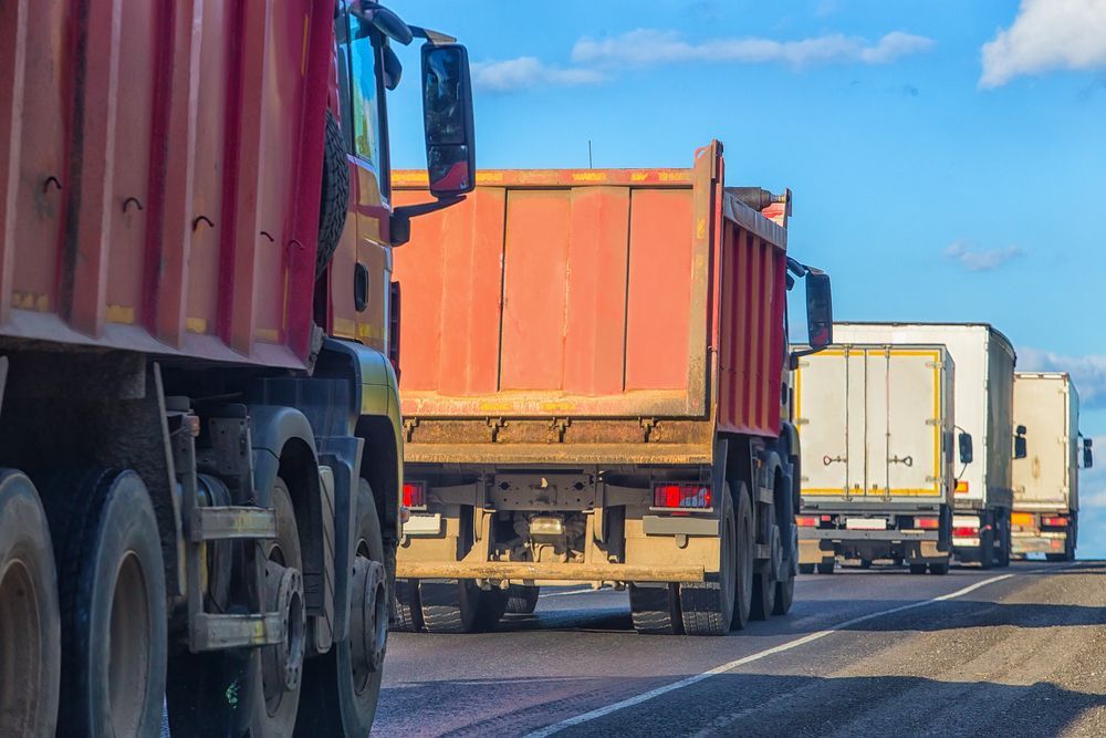 Red Dump Trucks and Trailers Driving on a Highway — Compass Equipment Hire in Woolgoolga, NSW