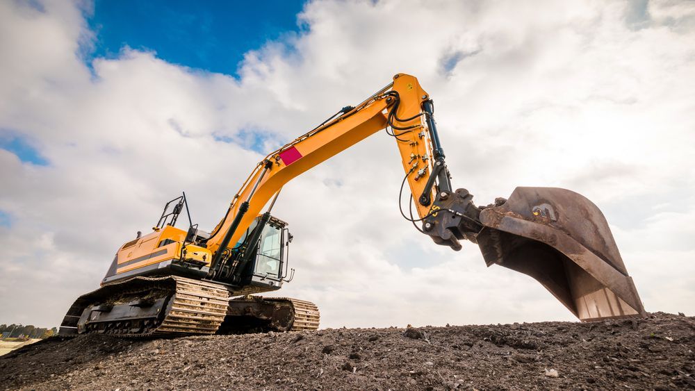Yellow Excavator Scoops Up Dirt on a Mound — Compass Equipment Hire in Byron Bay, NSW