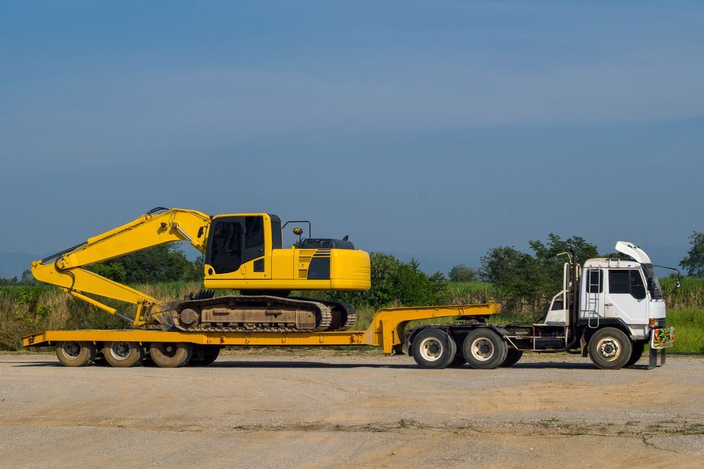 Yellow Excavator on a Flatbed Trailer Being Pulled — Compass Equipment Hire in Maclean, NSW
