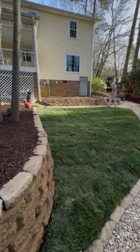 House with a lush green lawn, trees, and blue sky.