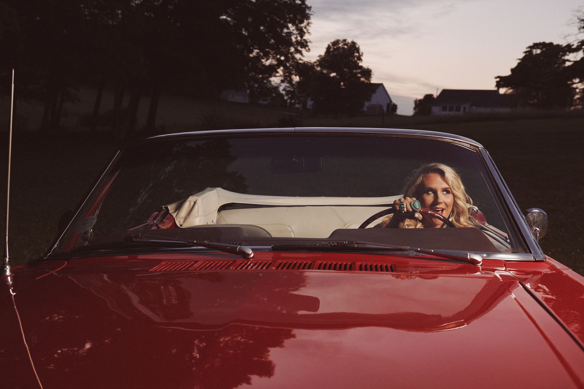 Star Jackson is sitting in a red car talking on a cell phone.