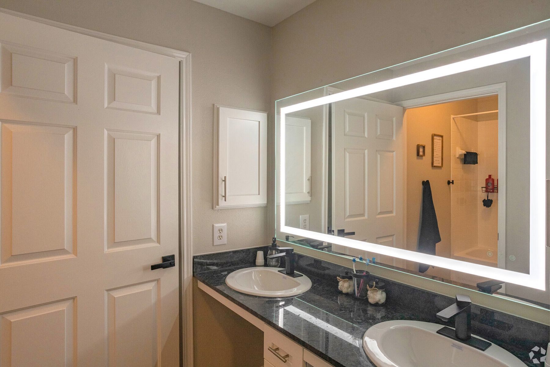 Private bathroom at Milestone Stillwater with large mirror, vanity lighting, and modern countertop.