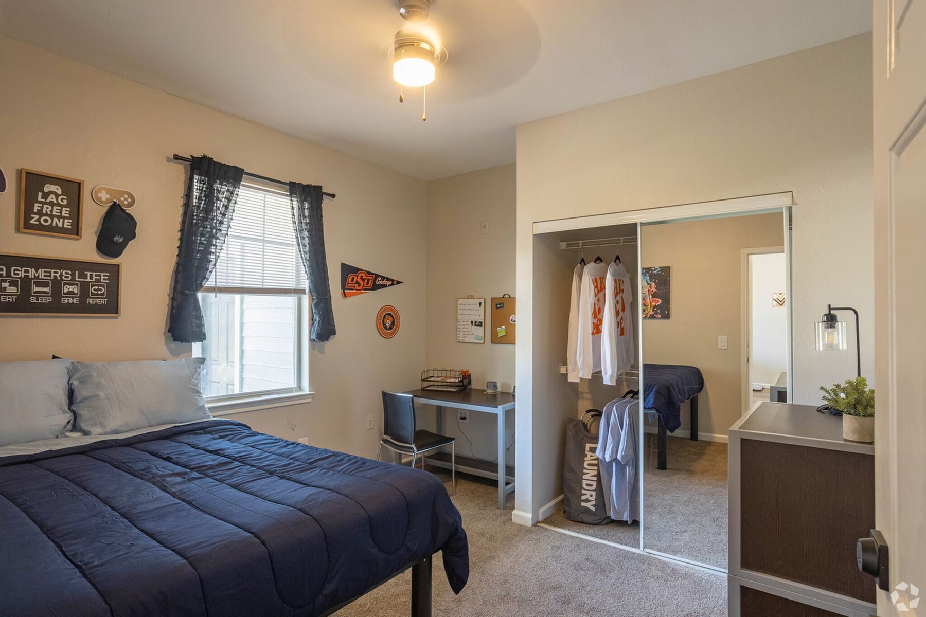 Cozy furnished student bedroom at Milestone Stillwater with window lighting and desk area.