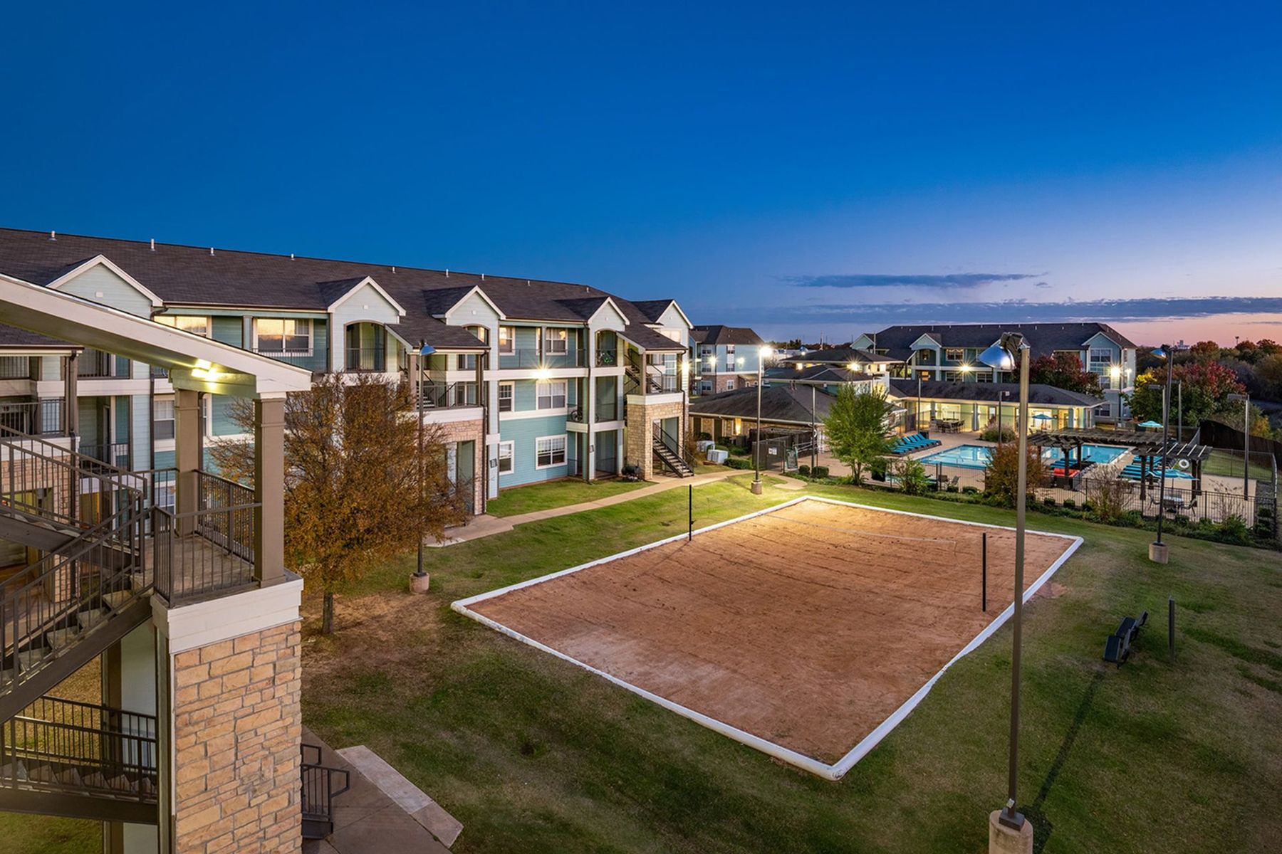 Milestone Stillwater student housing exterior with landscaped courtyard and sand volleyball court.