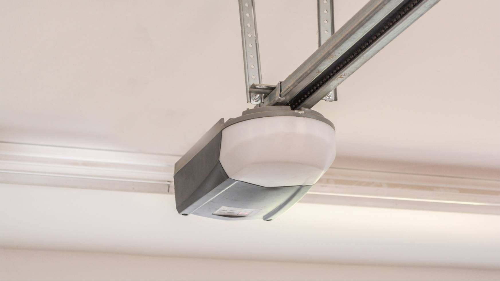 Garage door opener motor mounted on a ceiling rail, viewed from below.