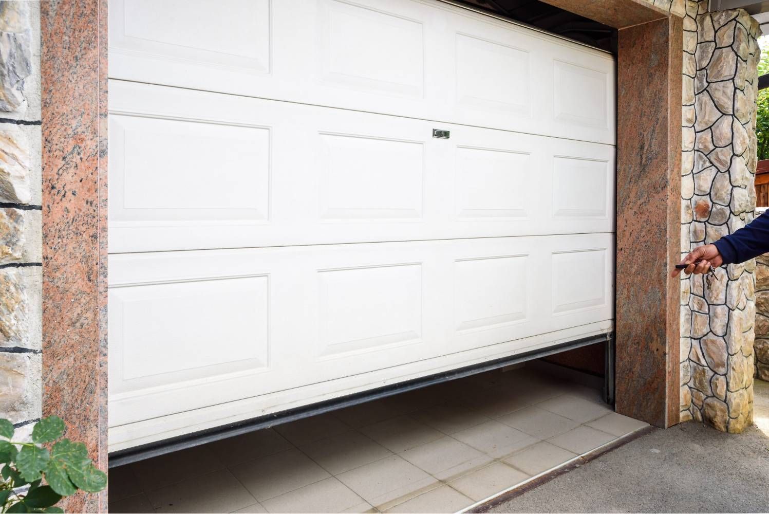 White garage door opening, with a person’s hand visible on the right side.