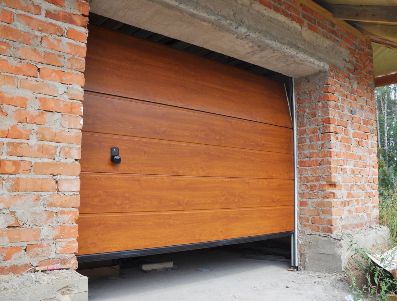 Wooden garage door partially open in a brick wall, showing a gap at the bottom.