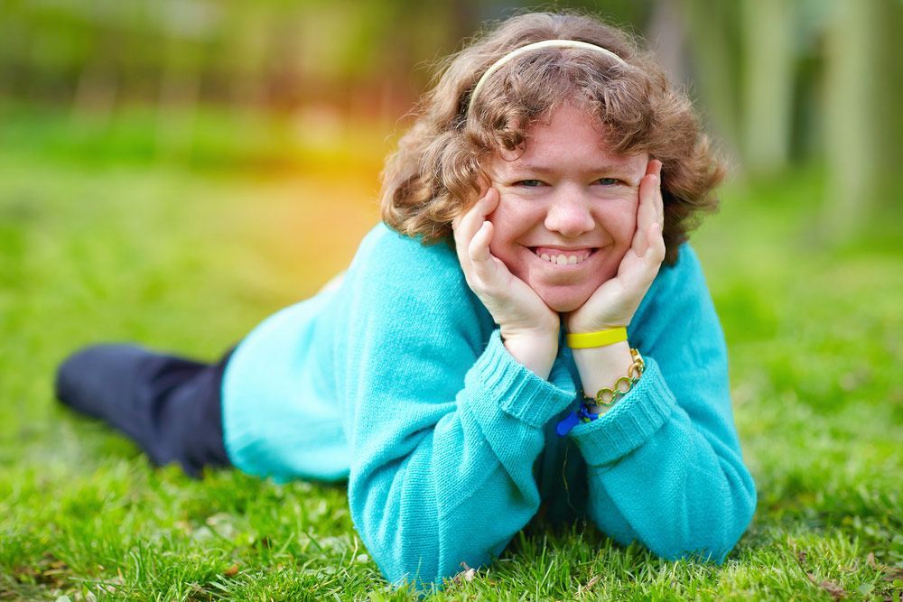 A Young Woman is Laying on Her Stomach in the Grass and Smiling — Learn to Live in Currajong, QLD