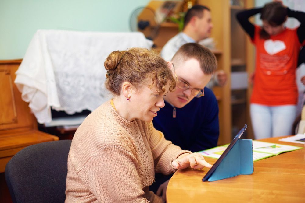 A Man and Woman at a Table Staring at a Digital Tablet — Learn to Live in Aitkenvale, QLD