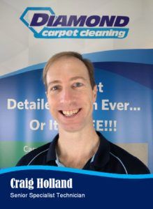 Craig Holland, Senior Specialist Technician for Diamond Carpet Cleaning, smiling in front of a company banner.