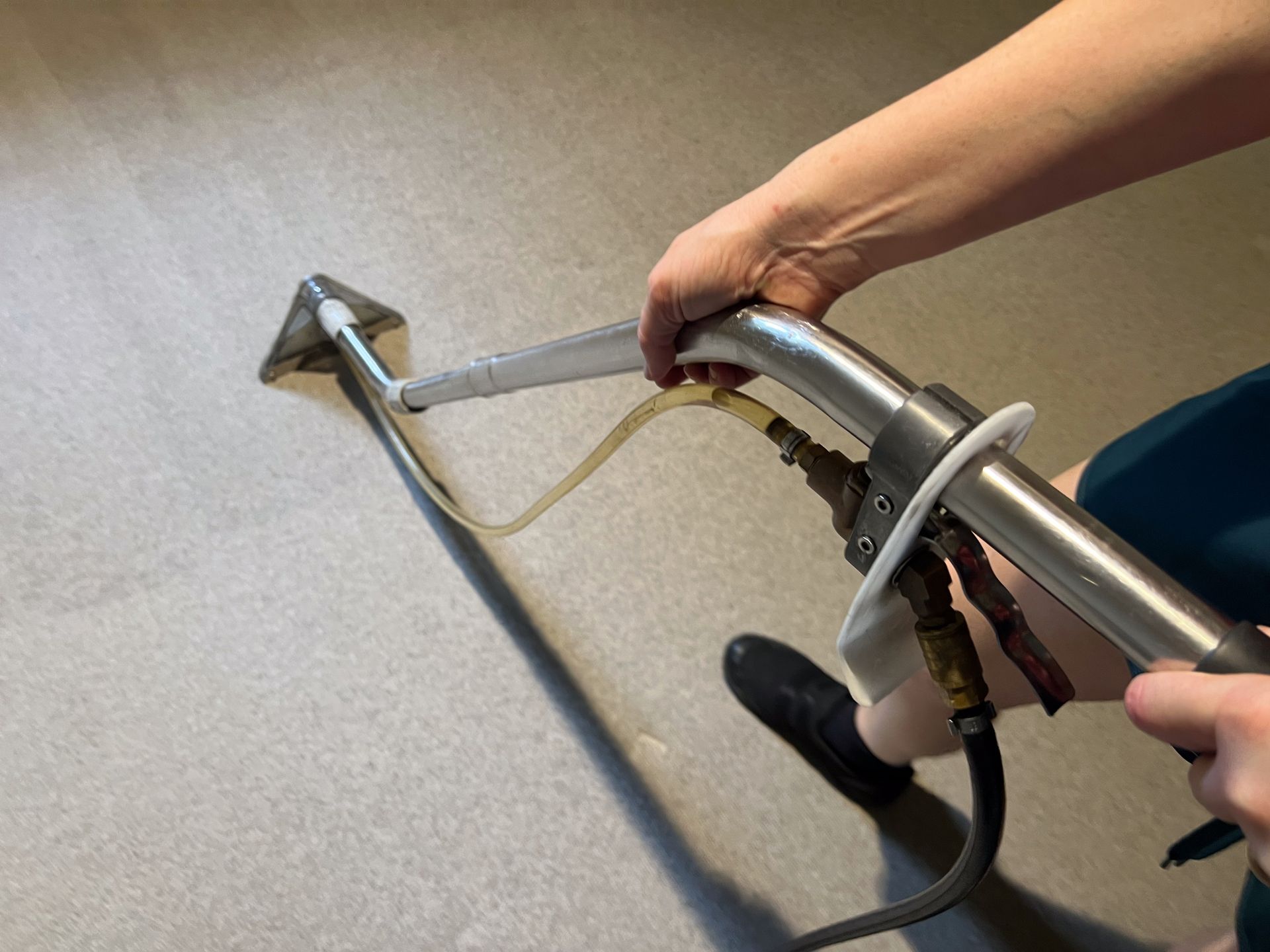 Person cleaning a carpet with an industrial cleaner.