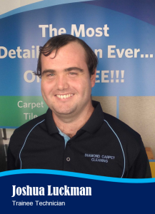 Smiling man, Joshua Luckman, wearing a Diamond Carpet Cleaning uniform. Blue and black backdrop.
