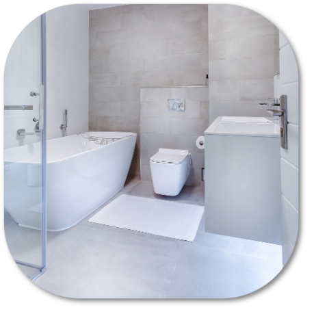 Modern bathroom with a white tub, toilet, and vanity against light gray tile.