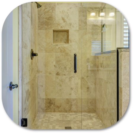 Beige tiled shower with glass door, grab bar, and recessed shelf.